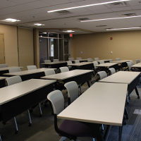 Tables and chairs are placed in a classroom setup.