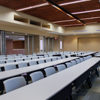 Tables and chairs are in a classroom setup in a large room.