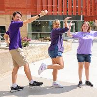 Three college students standing in the shape of a K, an S and a U.