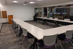 Movable tables and chairs in a presentation configuration with a podium in front.