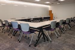 Movable tables and chairs in a presentation configuration with a podium in front.