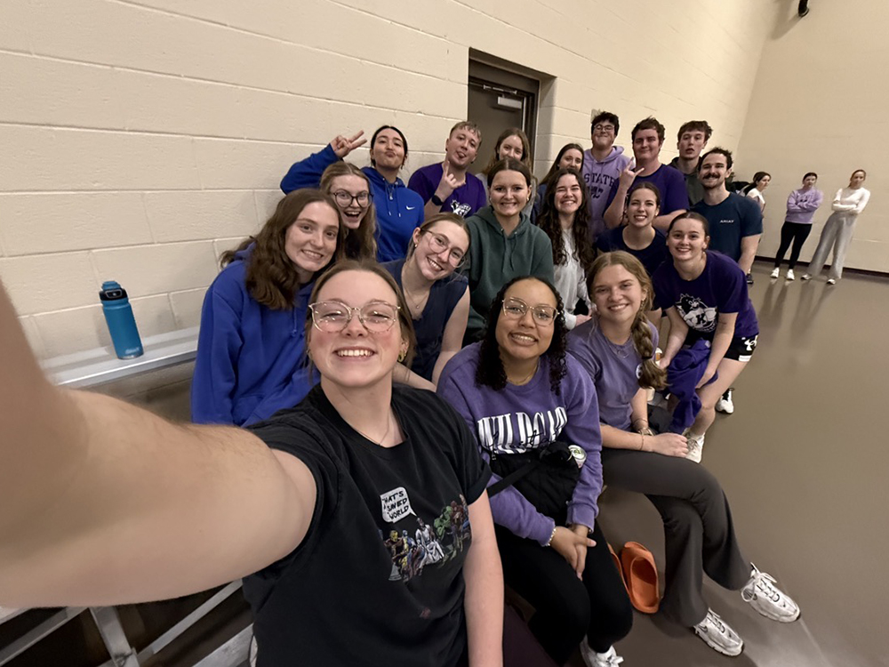 A group of students sitting in the stands and smiling