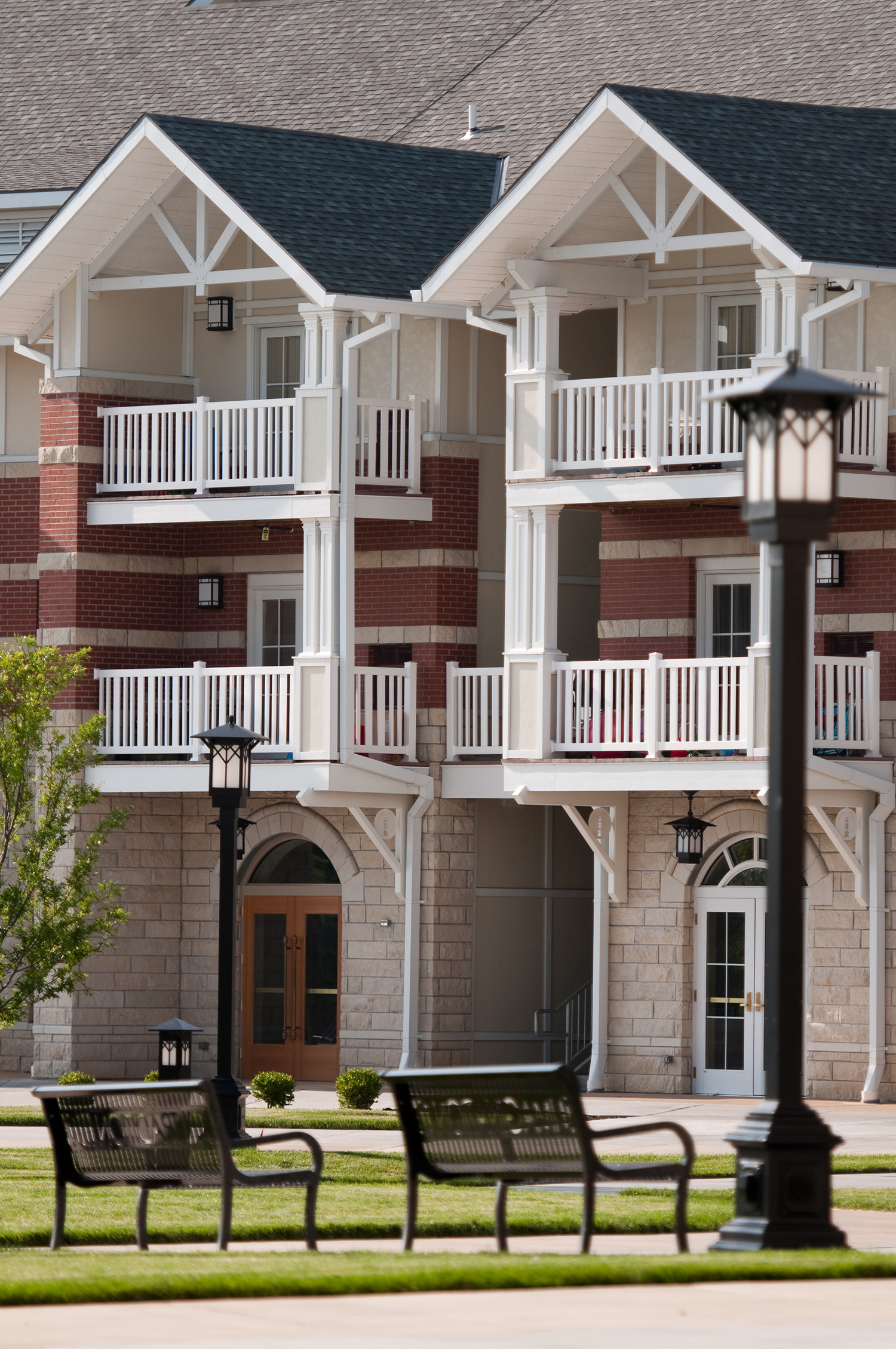 Exterior of apartment complex with benches and lamps near green space